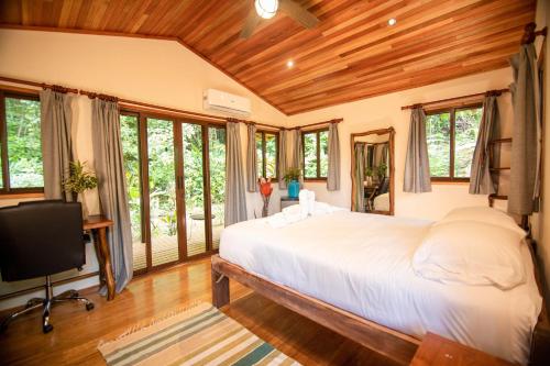 Schlafzimmer mit einem großen weißen Bett und Fenstern in der Unterkunft Selva Armonia Immersive Jungle Resort in Uvita