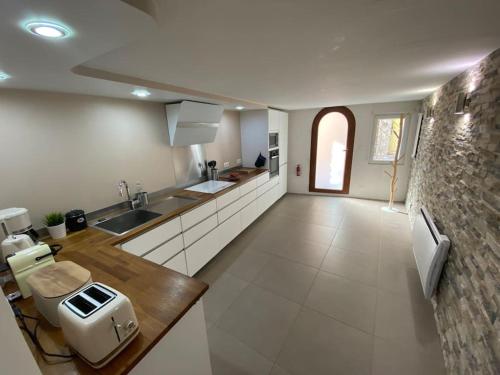 une grande cuisine avec des placards blancs et un comptoir dans l'établissement Lou Souleié, à Bagnols-en-Forêt