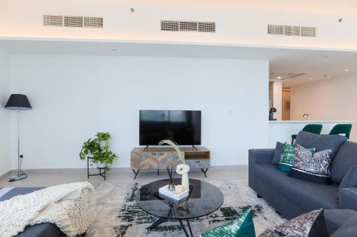 a living room with a blue couch and a tv at HiGuests - Spacious Apt Near Zabeel Park With Panoramic Views in Dubai