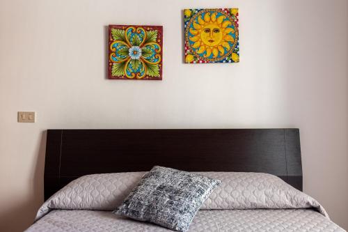 a bed with two pictures on the wall at Angy Apartment in Terrasini
