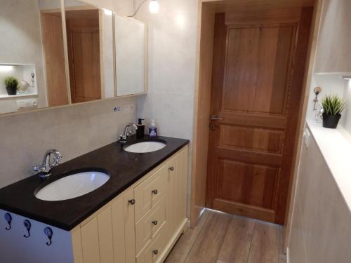 uma casa de banho com 2 lavatórios e uma porta de madeira em Holiday Home Cuylehoeve em Leffinge