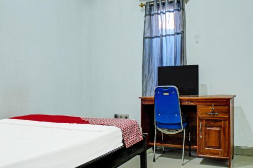 a bedroom with a bed and a desk and a blue chair at OYO 91720 Hotel Yotowawa in Kupang