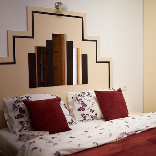 a bedroom with a bed with red and white pillows at Klaudia Vendégház in Mórahalom