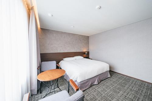 a hotel room with a bed and a table and chairs at Hotel With City in Jeju