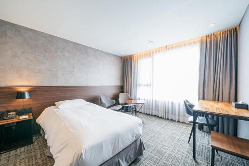 a hotel room with a bed and a desk at Hotel With City in Jeju