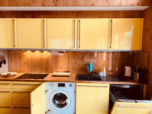 a kitchen with a washing machine and wooden cabinets at Chalet Breithorn- Perfect for Holiday with Amazing View! in Obergesteln