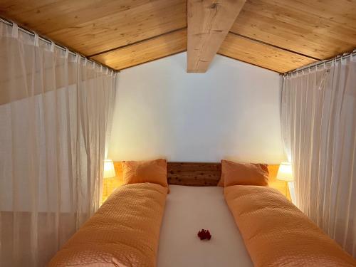 a bed in a room with white curtains at Chalet Breithorn- Perfect for Holiday with Amazing View! in Obergesteln