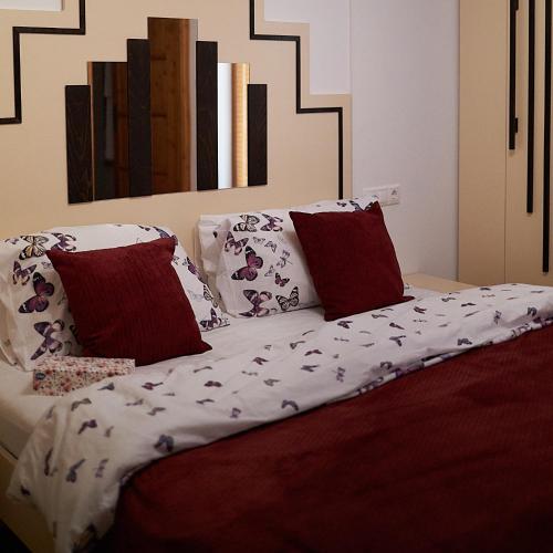 a bed with red and white sheets and pillows at Klaudia Vendégház in Mórahalom