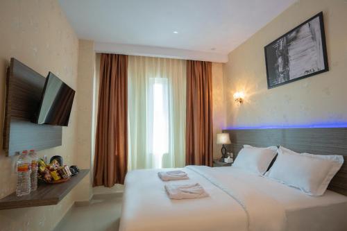 a hotel room with a large white bed and a television at De'Tonga Hotel in Medan