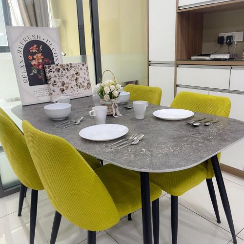a dining room table with yellow chairs around it at Atria Sofo Suites - Petaling Jaya in Petaling Jaya