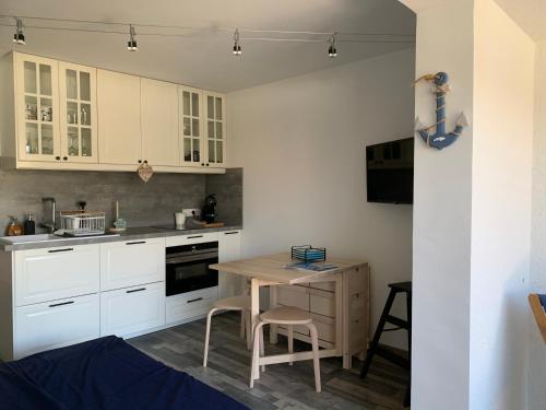 une cuisine avec des armoires blanches et une table en bois dans l'établissement Appartement 4 étoiles Golfe de St Tropez, à Cogolin