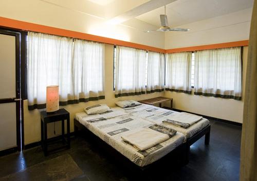 a bedroom with a large bed in a room with windows at Auromode Apartments Auroville in Auroville
