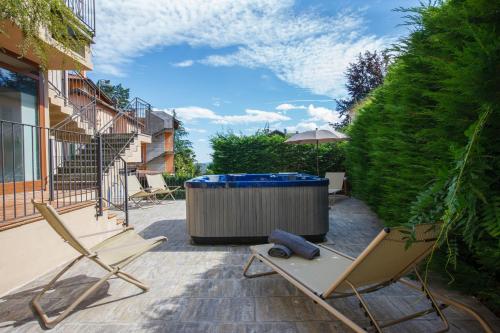 a couple of chairs and a hot tub on a patio at Hotel Milano & Apartments in Miazzina