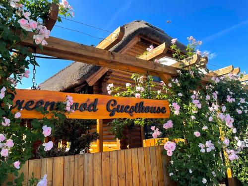 a sign in front of a house with flowers at Greenwood Rönkház in Gárdony