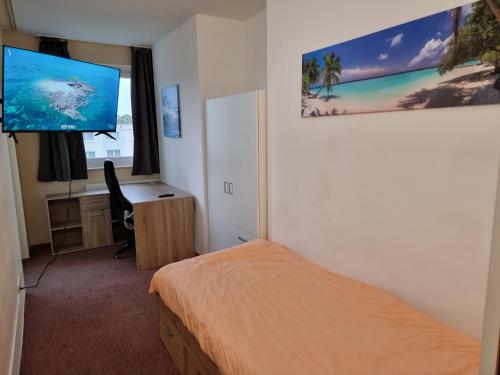 Schlafzimmer mit einem Bett, einem Schreibtisch und einem Flachbild-TV in der Unterkunft Onkel Tom Amazonien & Ozeanien in Paderborn