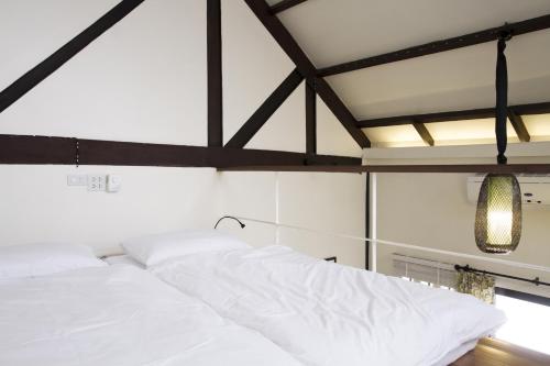 a bedroom with a white bed and a chandelier at Baan Luang Rajamaitri Historic Inn in Chanthaburi