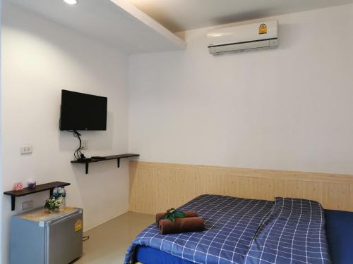 a bedroom with a blue bed and a flat screen tv at De​ Lanta place in Ko Lanta