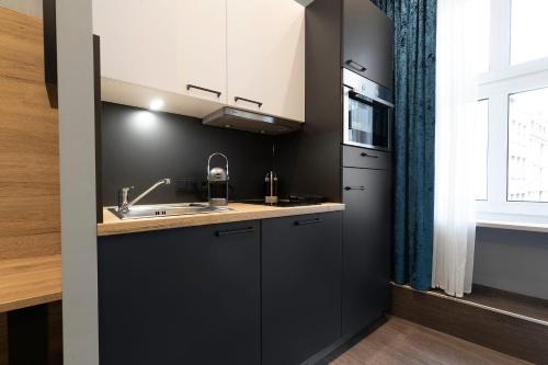a kitchen with black cabinets and a sink and a window at Aparthotel by dasPaul in Nürnberg