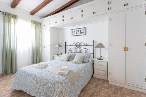 a white bedroom with a large bed with two towels on it at Villa Benama in Torrox