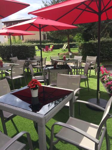 a group of tables and chairs with red umbrellas at Residhome Val d'Europe in Montévrain