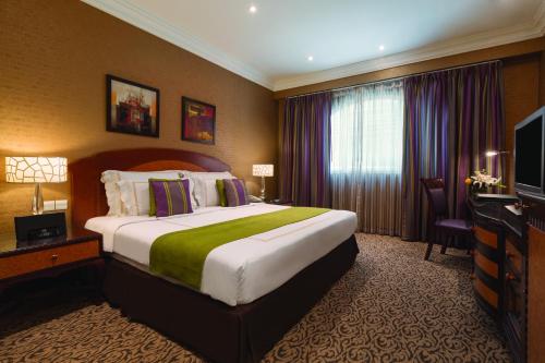 a bedroom with a large bed and a large window at Wyndham Grand Regency Doha in Doha