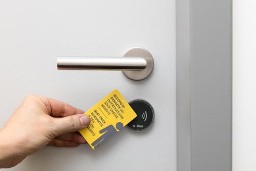 a person holding a yellow tag on a door at Buddy Hotel in Munich