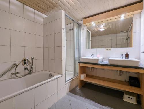 a bathroom with two sinks and a tub and a mirror at Landhaus Hoher in Oberteuringen