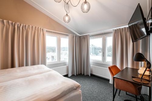 a hotel room with a bed and a desk and windows at Rija Fonnental Design Hotel Tallinn in Tallinn