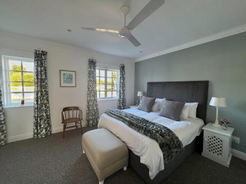 a bedroom with a large bed and two windows at Greenhill Farm Cape Dutch Cottage Plettenberg Bay - 1 Bedroom Private Cottage in Plettenberg Bay
