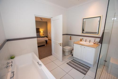uma casa de banho com uma banheira, um lavatório e um WC. em Greenhill Farm Cape Dutch Cottage Plettenberg Bay - 1 Bedroom Private Cottage em Plettenberg Bay