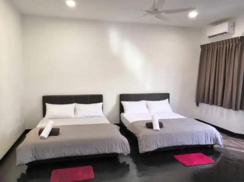 two beds in a room with red pillows at Flora Homestay in Taman Flora in Batu Pahat