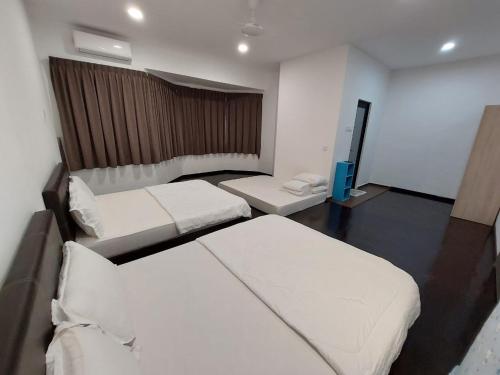 a hotel room with two beds and a tv at Flora Homestay in Taman Flora in Batu Pahat