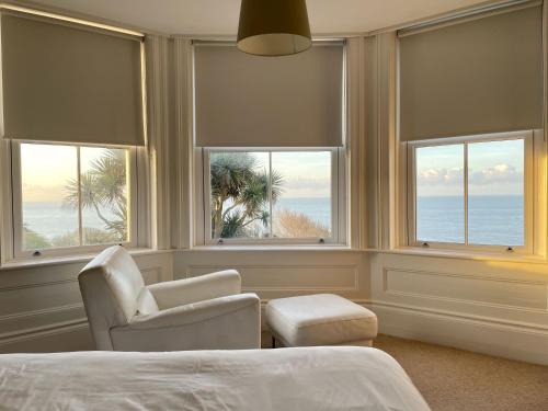 a bedroom with a bed and a chair and windows at St Catherine's Lookout in Niton