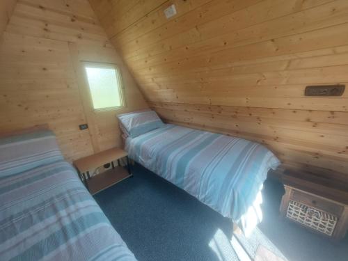 1 Schlafzimmer mit 2 Betten in einem Blockhaus in der Unterkunft Rum Bridge "Owl Watch" wooden tipi in Sudbury