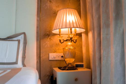 a lamp sitting on a table next to a bed at Royal 9 hotel & Banquet in Meerut