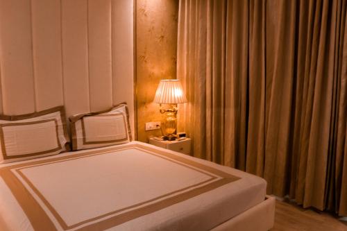 a bedroom with a bed and a lamp and curtains at Royal 9 hotel & Banquet in Meerut