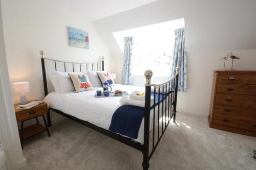 a bedroom with a bed and a dresser and a window at 4 The Dunes, Thorpeness in Thorpeness