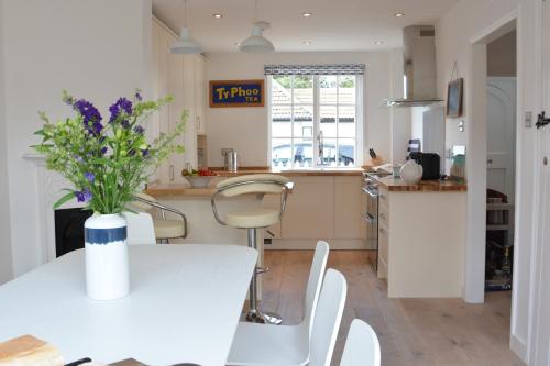 a kitchen with a table with a vase of flowers on it at 4 The Dunes, Thorpeness in Thorpeness