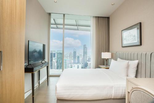 a hotel room with a bed and a large window at Magnolias Ratchadamri Boulevard Serviced Residences in Bangkok