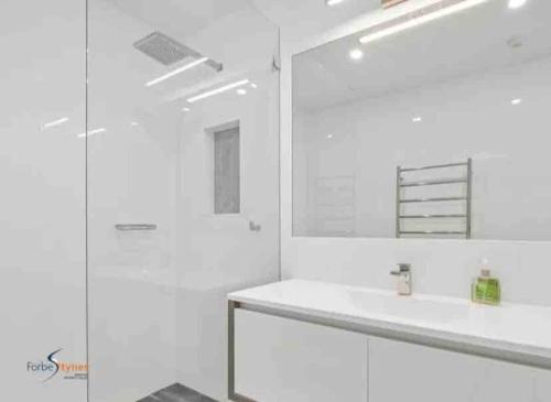 Baño blanco con lavabo y espejo en Stylish Thredbo Alpine Chalet + Garage in Tranquil Setting, en Thredbo