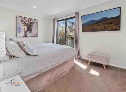 1 dormitorio con cama y ventana grande en Stylish Thredbo Alpine Chalet + Garage in Tranquil Setting, en Thredbo