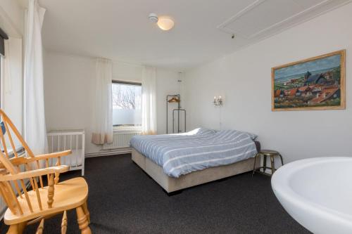 Holidayhouse - Oranjeplein 23 Zoutelande في زوتلاند: غرفة نوم مع سرير وحوض استحمام ومغسلة