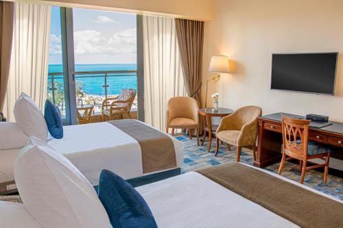 a hotel room with two beds and a desk and a television at Helnan Royal Palestine Hotel - Montazah Gardens in Alexandria