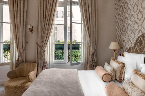 a bedroom with a bed and a chair and a window at Relais Christine in Paris