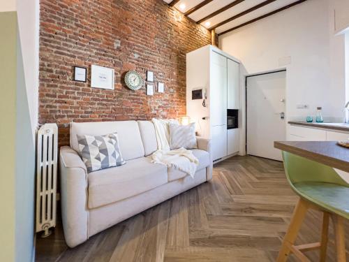 a living room with a white couch and a brick wall at Emma's home Monza in Monza