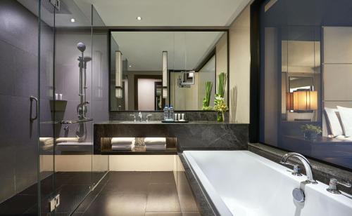 a bathroom with a tub and a large mirror at ARTOTEL Suites Mangkuluhur Jakarta in Jakarta