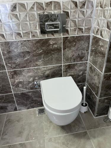 a bathroom with a white toilet in a tiled wall at Belka Golf Residence Exclusive Apt Poolside in Belek