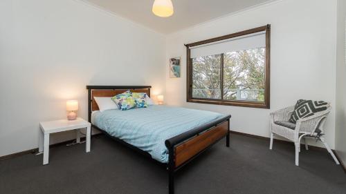 a bedroom with a bed and a window and a chair at Veronica Lodge in Inverloch