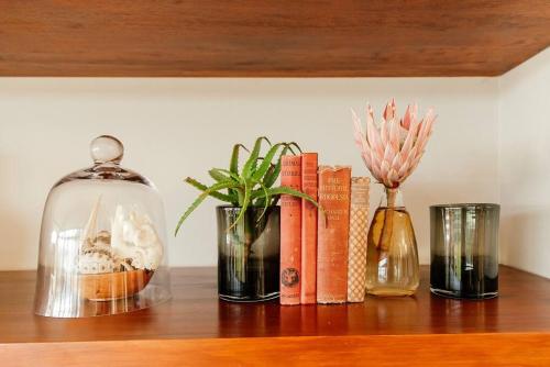 a shelf with books and vases and a glass jar at Cloud 9 Luxury Eco Villa in Sedgefield
