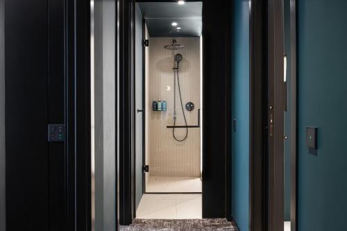 uma cabina de duche ao nível do chão numa casa de banho com uma porta de vidro em Novotel Living Almaty Jetisu em Almaty